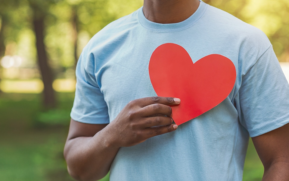 Man holding heart shaped paper by his chest