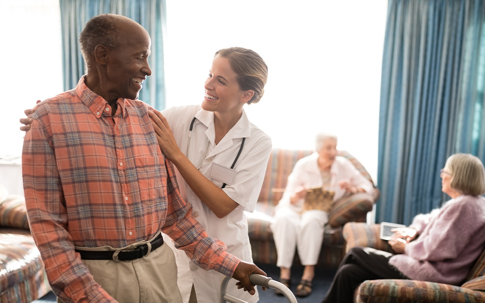 Smiling senior man with walker looking at female doctor. Click for answers to the question: how much does senior living cost?