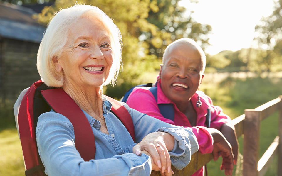 Portrait Of Two Female Senior Friends Hiking In Countryside. Click for 8 spring activities for seniors.