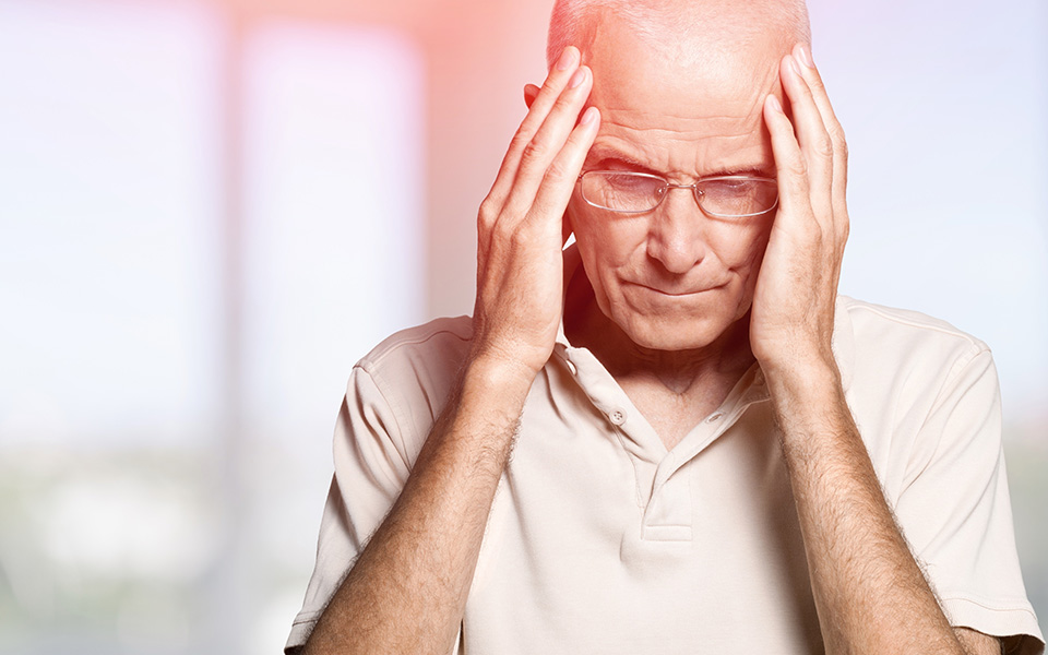 Elderly man holding head in pain. May is National Stoke Awareness Month.