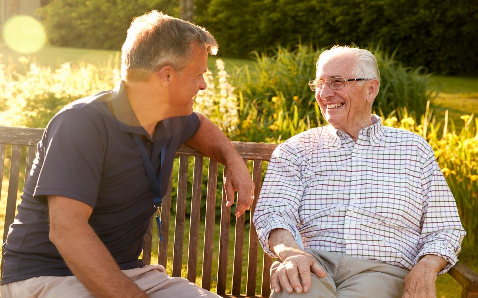 Father and son sitting on a bench at an assisted living facility